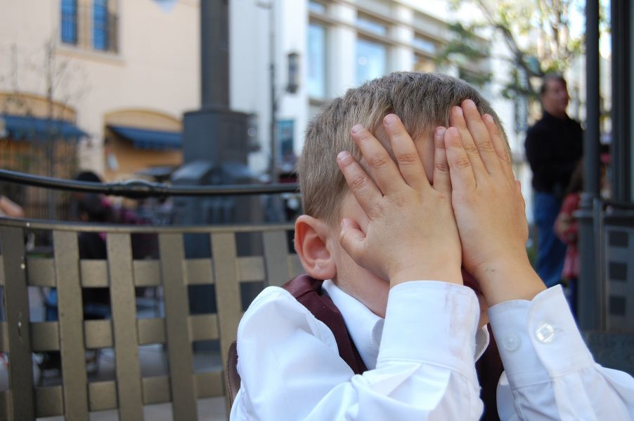 Junges Kind mit Händen im Gesicht, Gefühl von Missverständnis